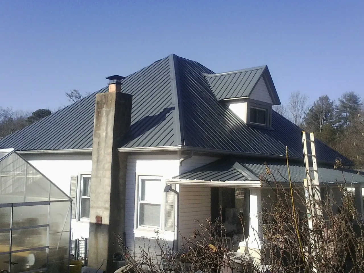Dark blue standing seam metal roof on a white farmhouse with dormer — Slate & Tile Roof Repair by Roofing Brothers in Palos Hills