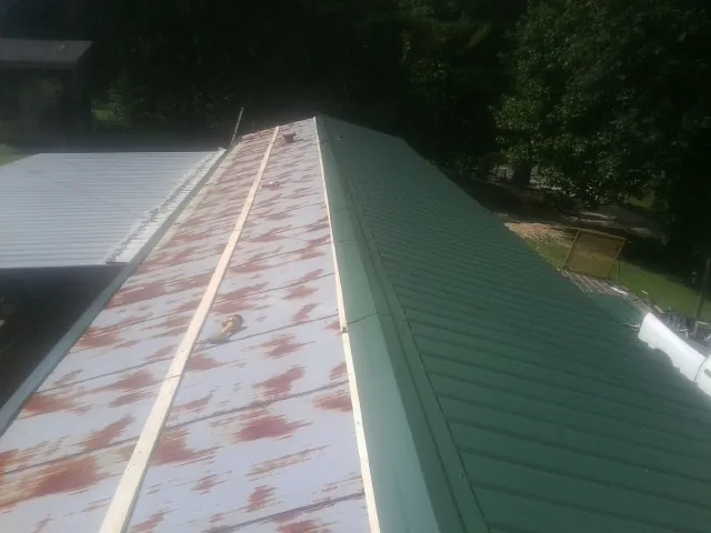 Old rusted panels beside newly installed green metal roofing — Wind Damage Roof Repair by Roofing Brothers in Palos Hills