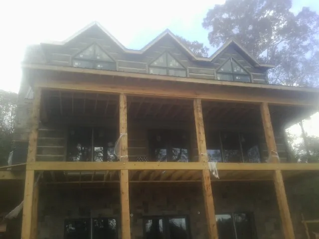 Dormers and porch framing on a large log home under construction — Roof Coating work by our crew in Palos Hills
