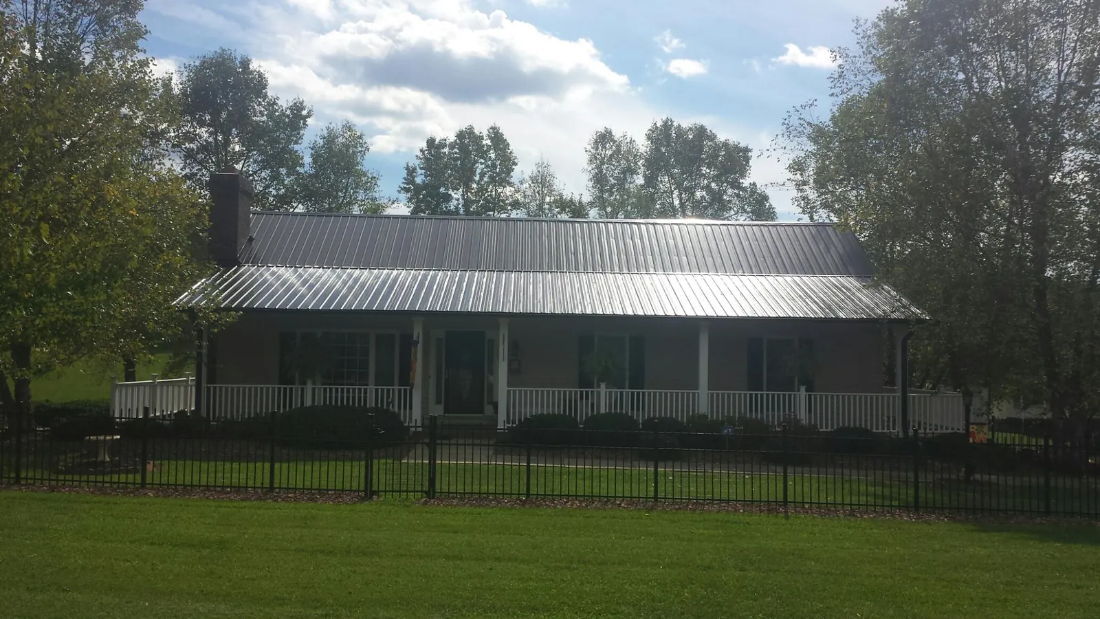 Gray metal roof on a brick ranch with a full width front porch — Gutter Guard Installation work by our crew in Palos Hills