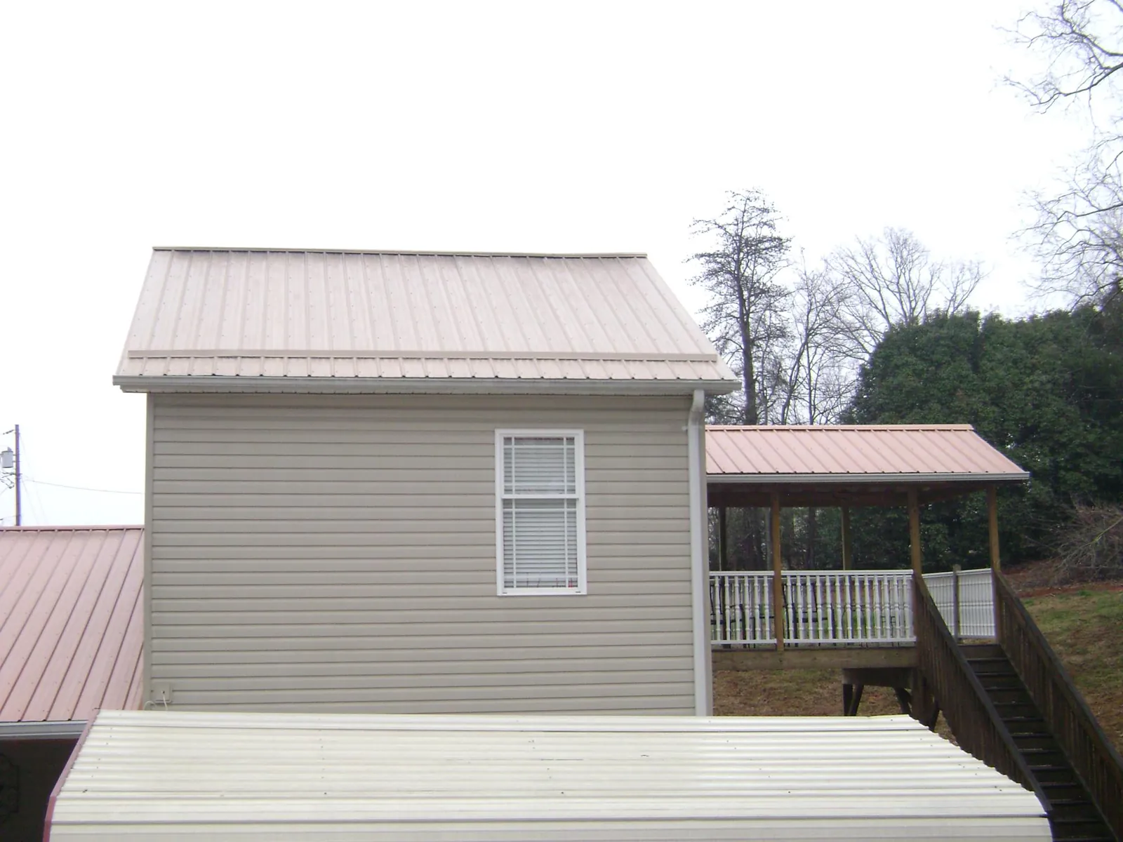 Tan metal roofs on a two story addition and attached porch, from a Roof Replacement job in Palos Hills