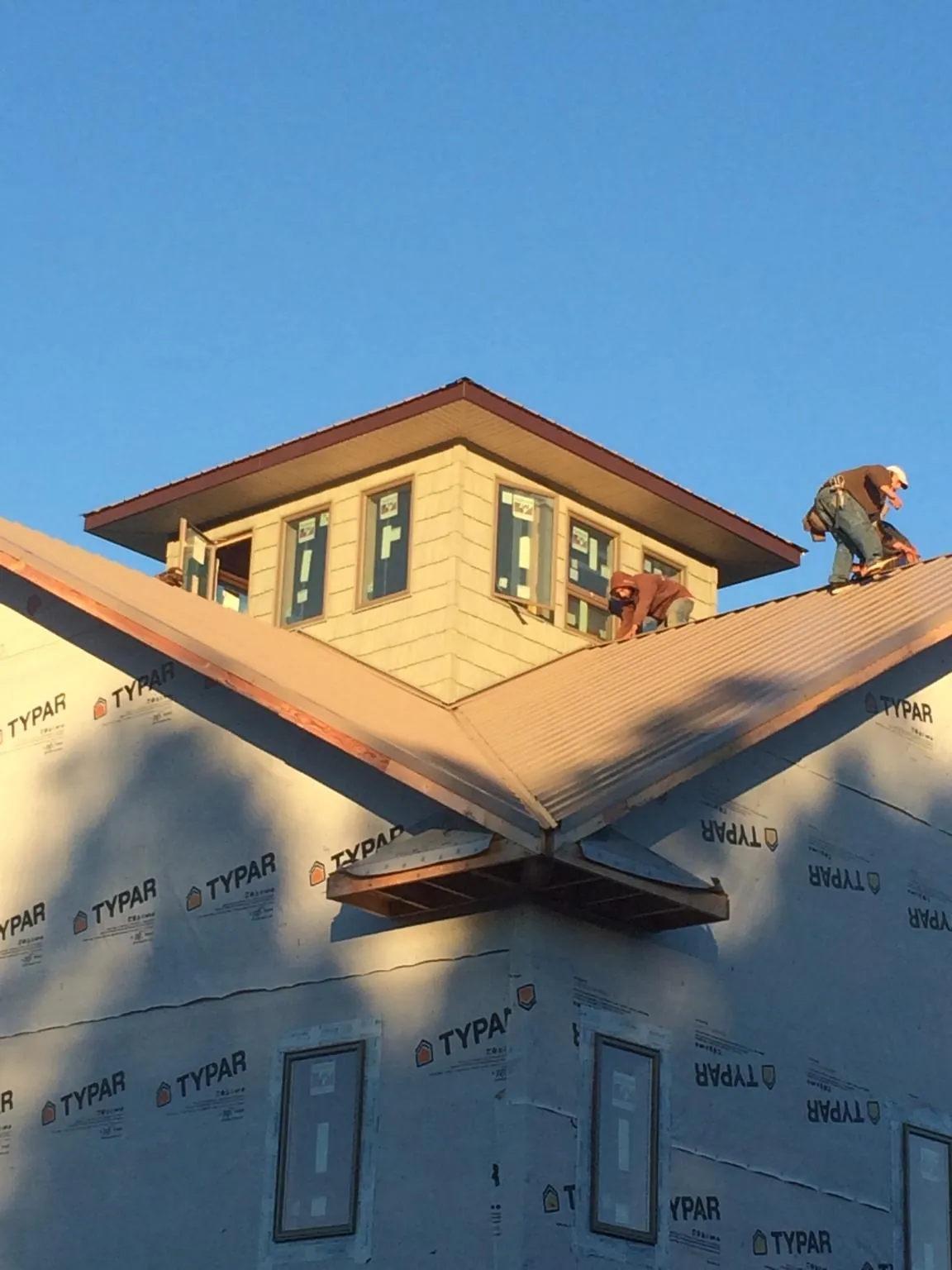 Roofers working around a rooftop cupola on a new metal roof at sunset — Roof Waterproofing in Palos Hills by Roofing Brothers